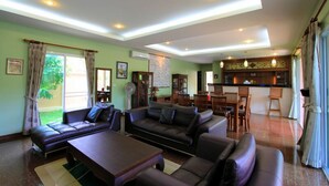 A spacious living area with a sofa set, a dining table, and chairs. There is a kitchen area in the background. - Villa Mukdara (Rawai)