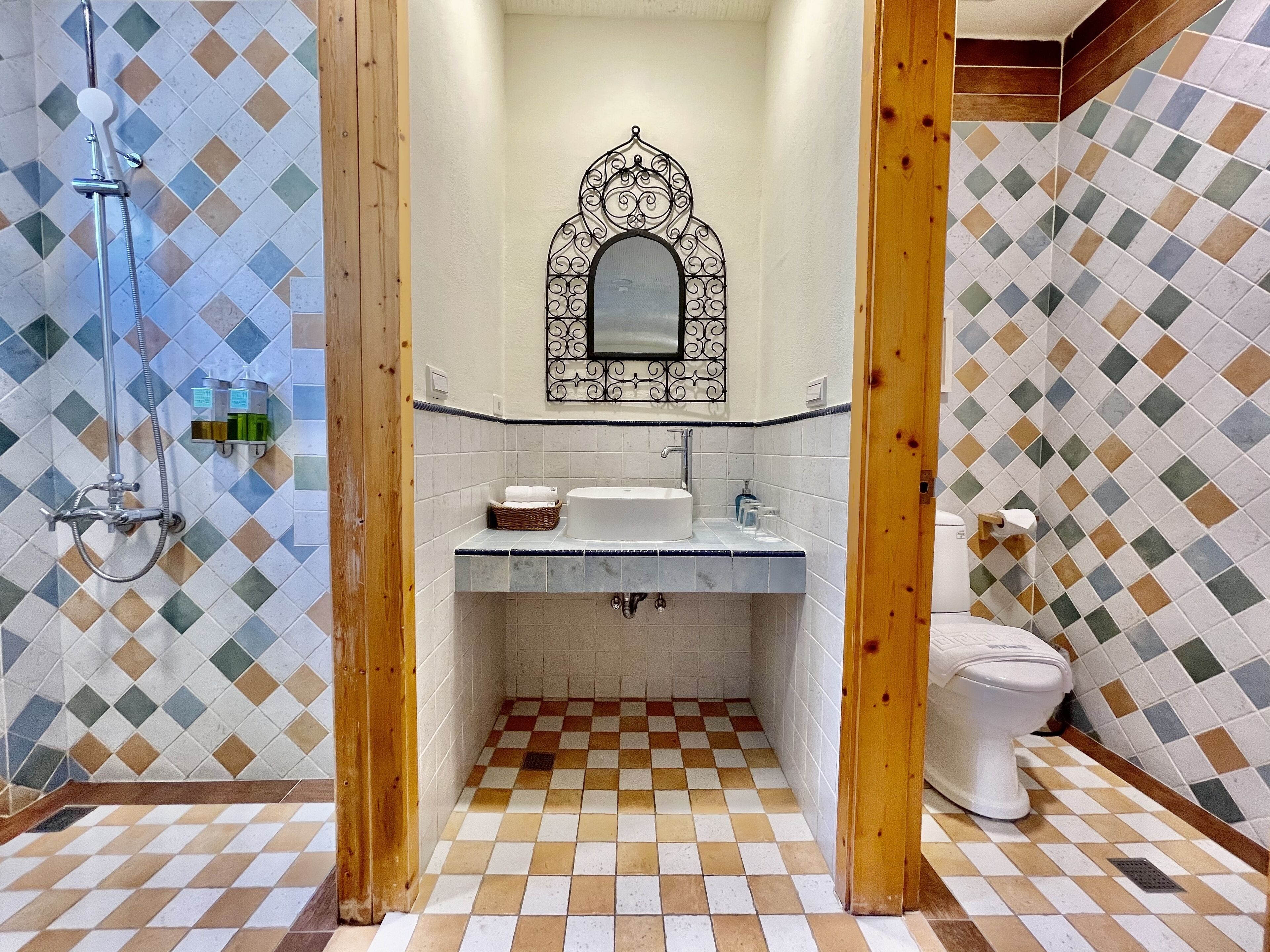 A bathroom with a checkered floor, a sink, a toilet, and a shower.