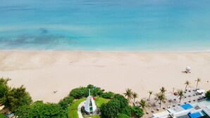 A beach with a clear view of the ocean, a sandy shore, and a small structure surrounded by greenery. - Spoondrift Hostal (Hengchun)