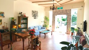 A spacious living room with a wooden ceiling, a sofa, a coffee table, and a bookshelf. - Spoondrift Hostal (Hengchun)