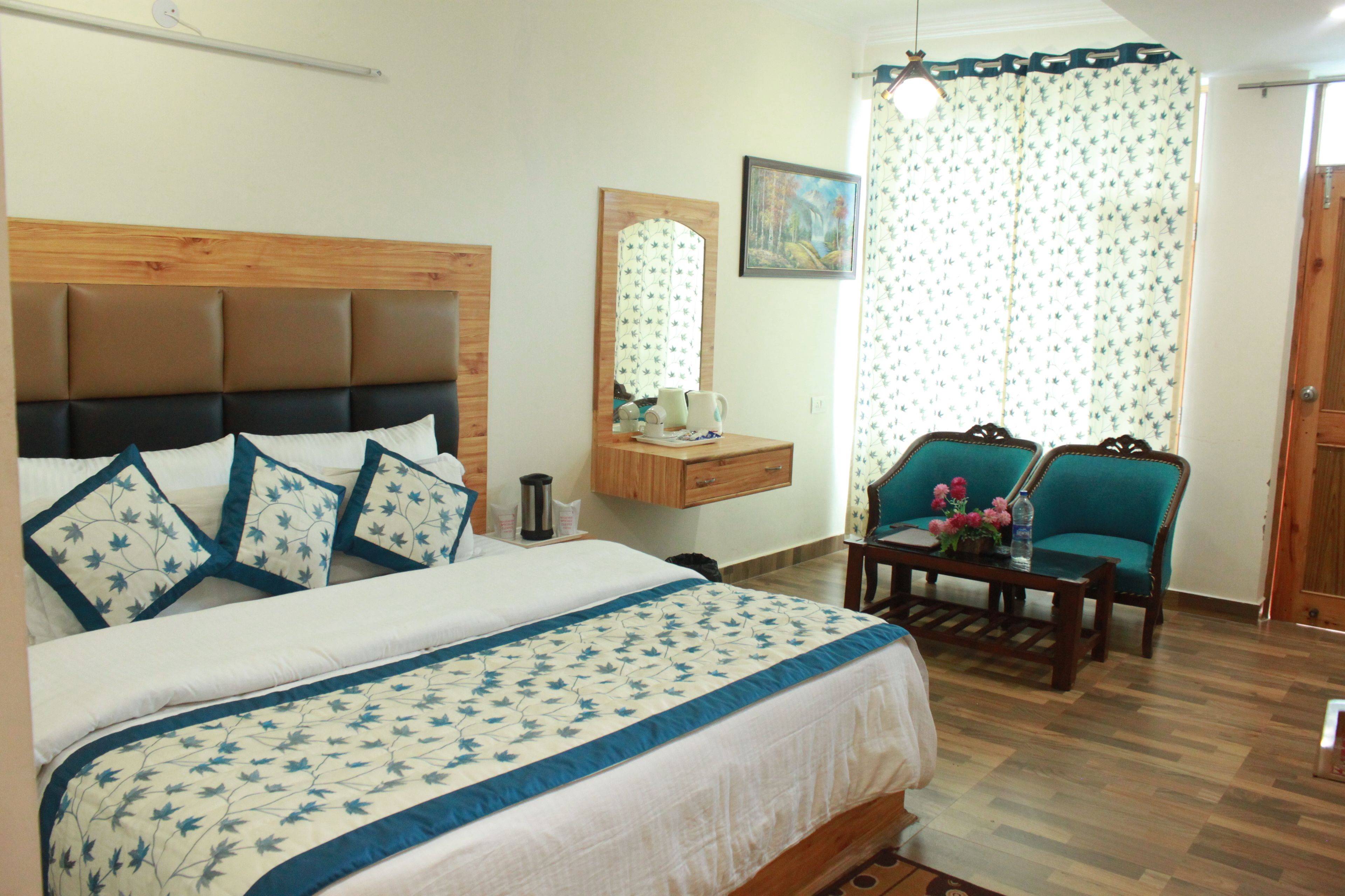 A bedroom with a bed, a nightstand, a mirror, a window with curtains, and two chairs.