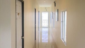 Un long couloir étroit, doté d’un sol brillant, de murs blancs et d’une porte au fond.