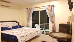 Une chambre d’hôtel avec un lit, un balcon avec une chaise, une petite table et un téléviseur.