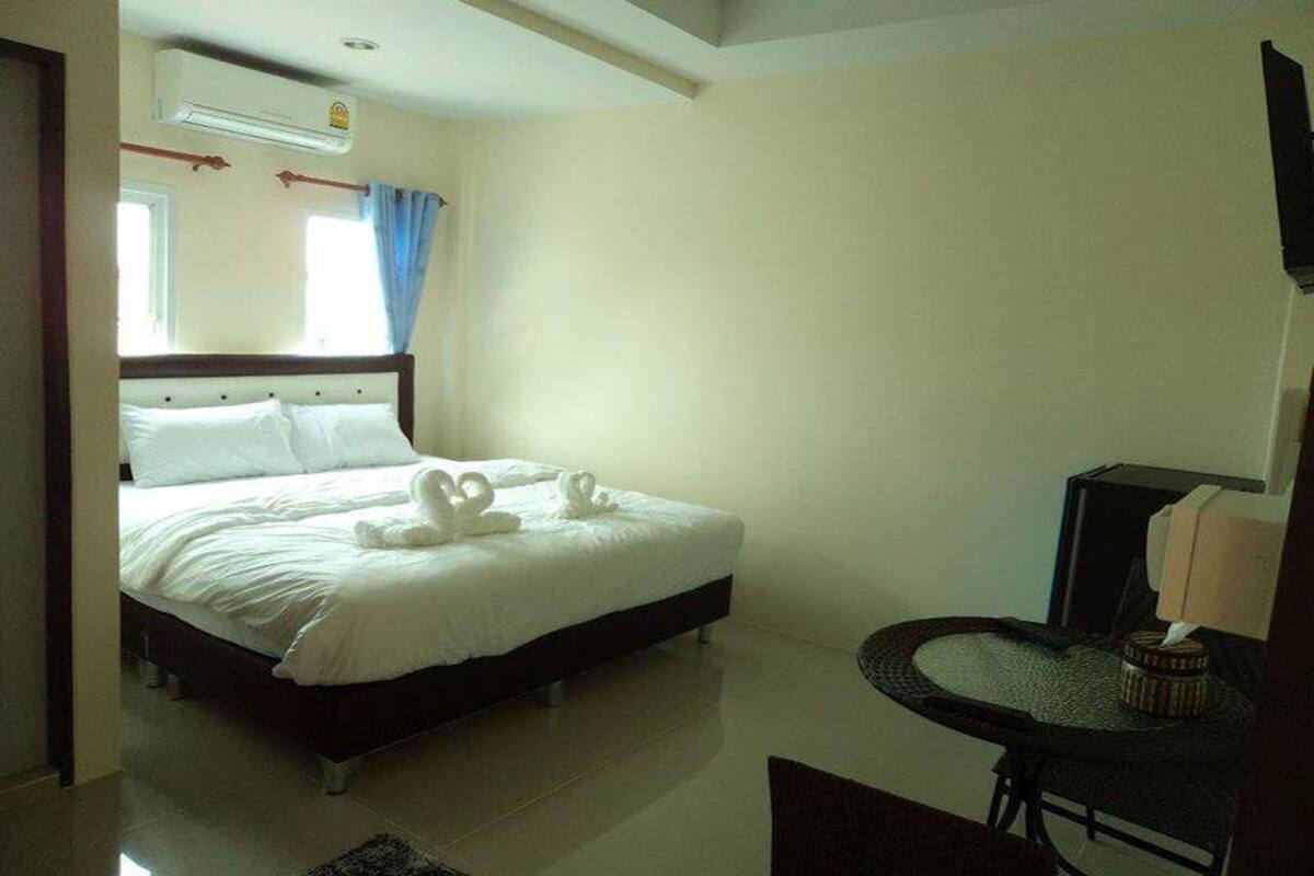 Une chambre d’hôtel avec un lit, une petite table, une chaise et un téléviseur.