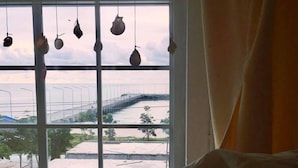 A room with a large window overlooking a bridge and a road. - Jetty Huahin Hostel (Hua Hin)