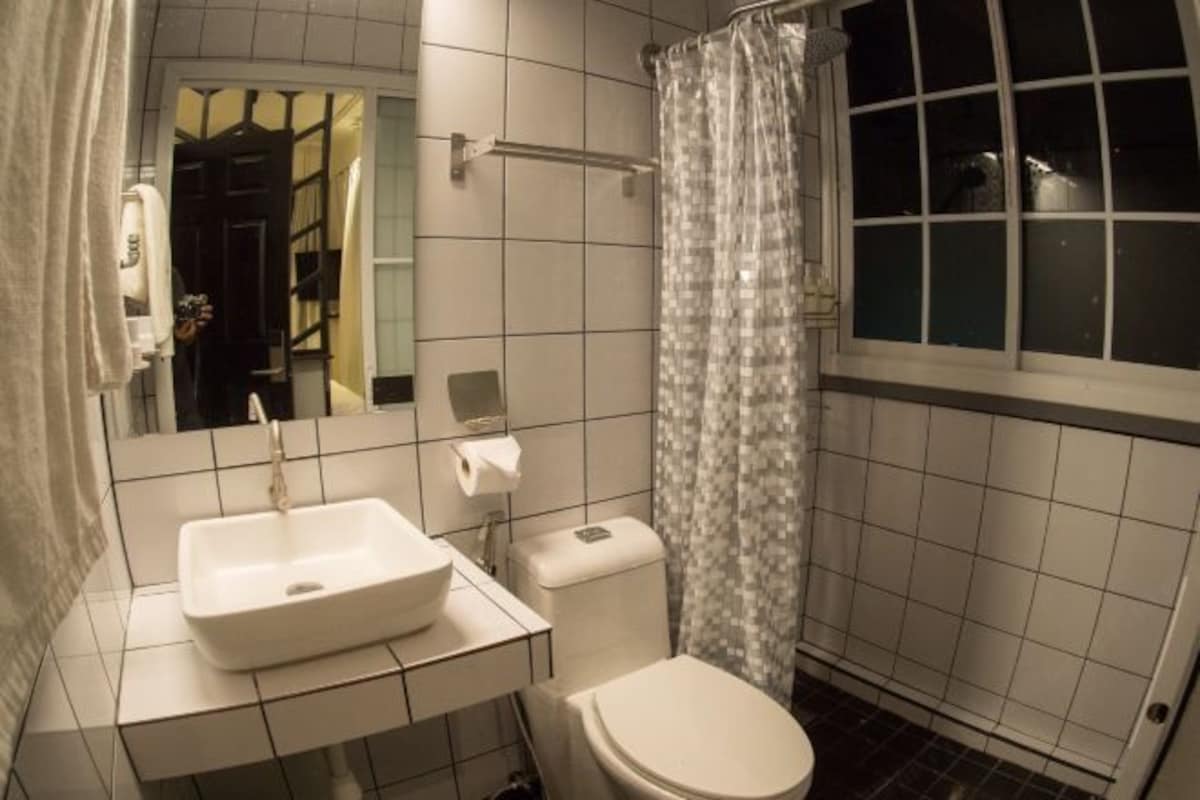 Un baño con lavamanos blanco, inodoro y cortina de ducha.