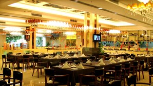 A spacious restaurant with multiple dining tables and chairs, a bar area with shelves of bottles, and a television screen. - Bolton Hotel Dongguan (Dongguan)