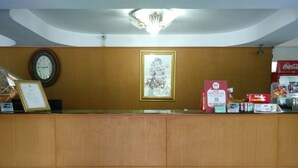 A reception desk with a clock, framed artwork, and various items on the counter. - Diamond Sweet Hotel (Bangkok)