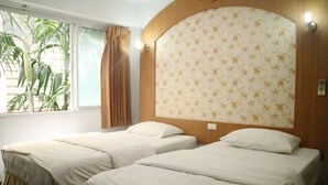 A hotel room with two single beds, a window with curtains, and a floral-patterned headboard. - Diamond Sweet Hotel (Bangkok)