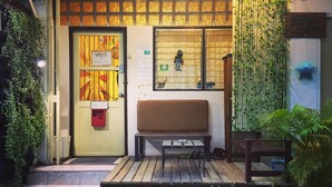 A building entrance with a bench, a door with a sign, and a wall with a mural.