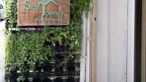 A vertical garden with a sign for 'Siam Journey Guesthouse'.