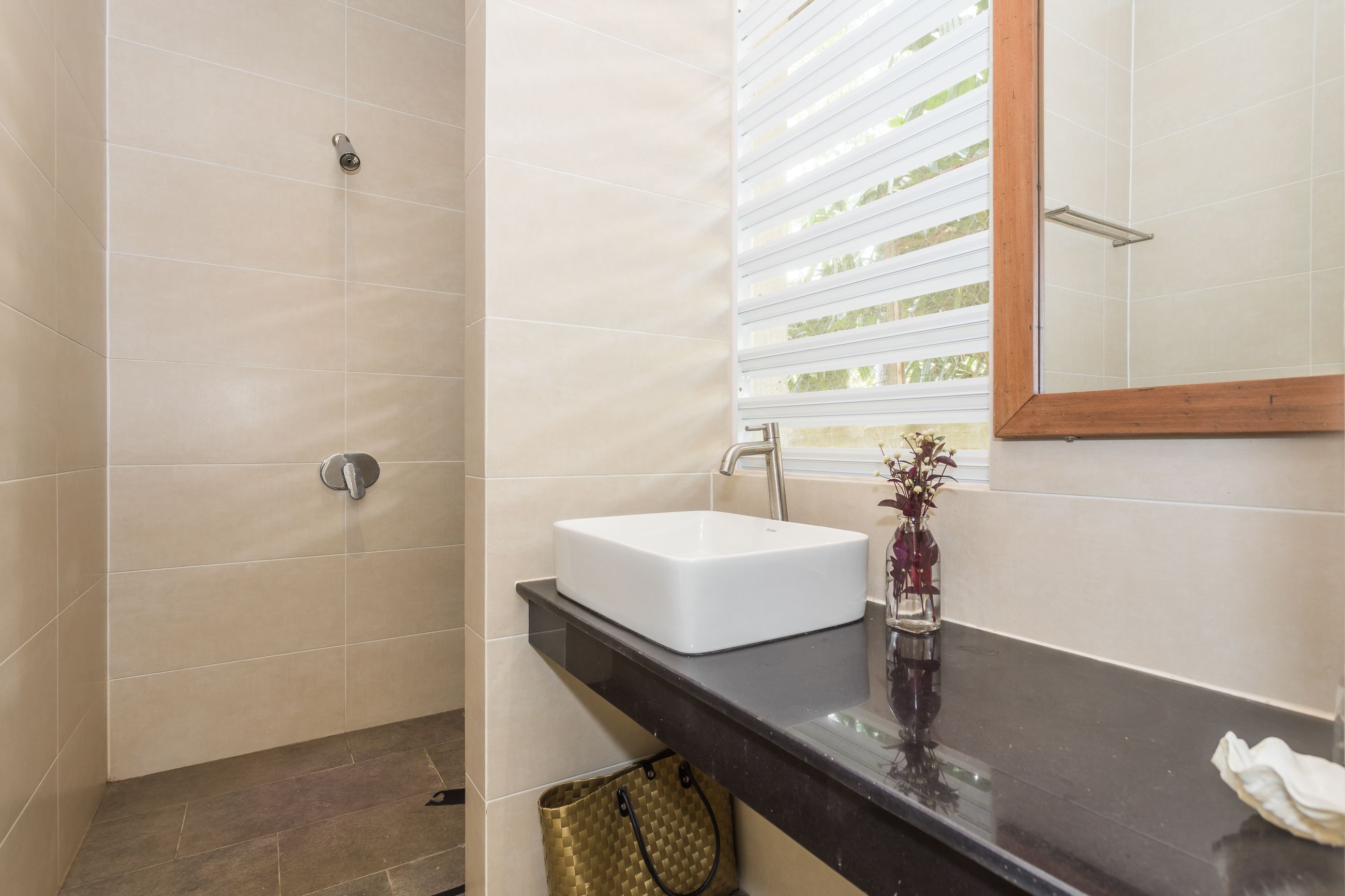 A bathroom with a white sink, a mirror, and a shower.