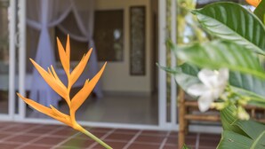 A room with a bed, a window, and a plant with orange flowers. - Le Forest Resort (Phu Quoc)