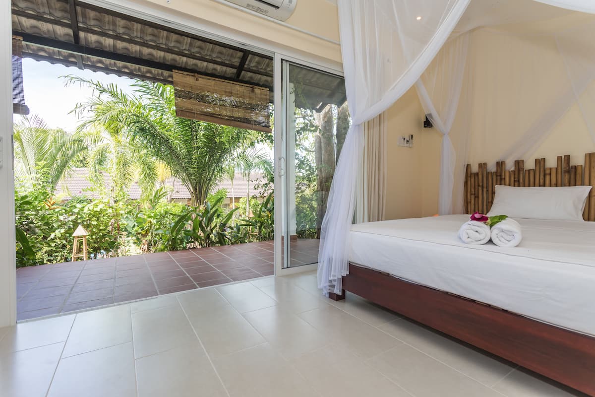 A bedroom with a large bed, white linens, and a canopy.
