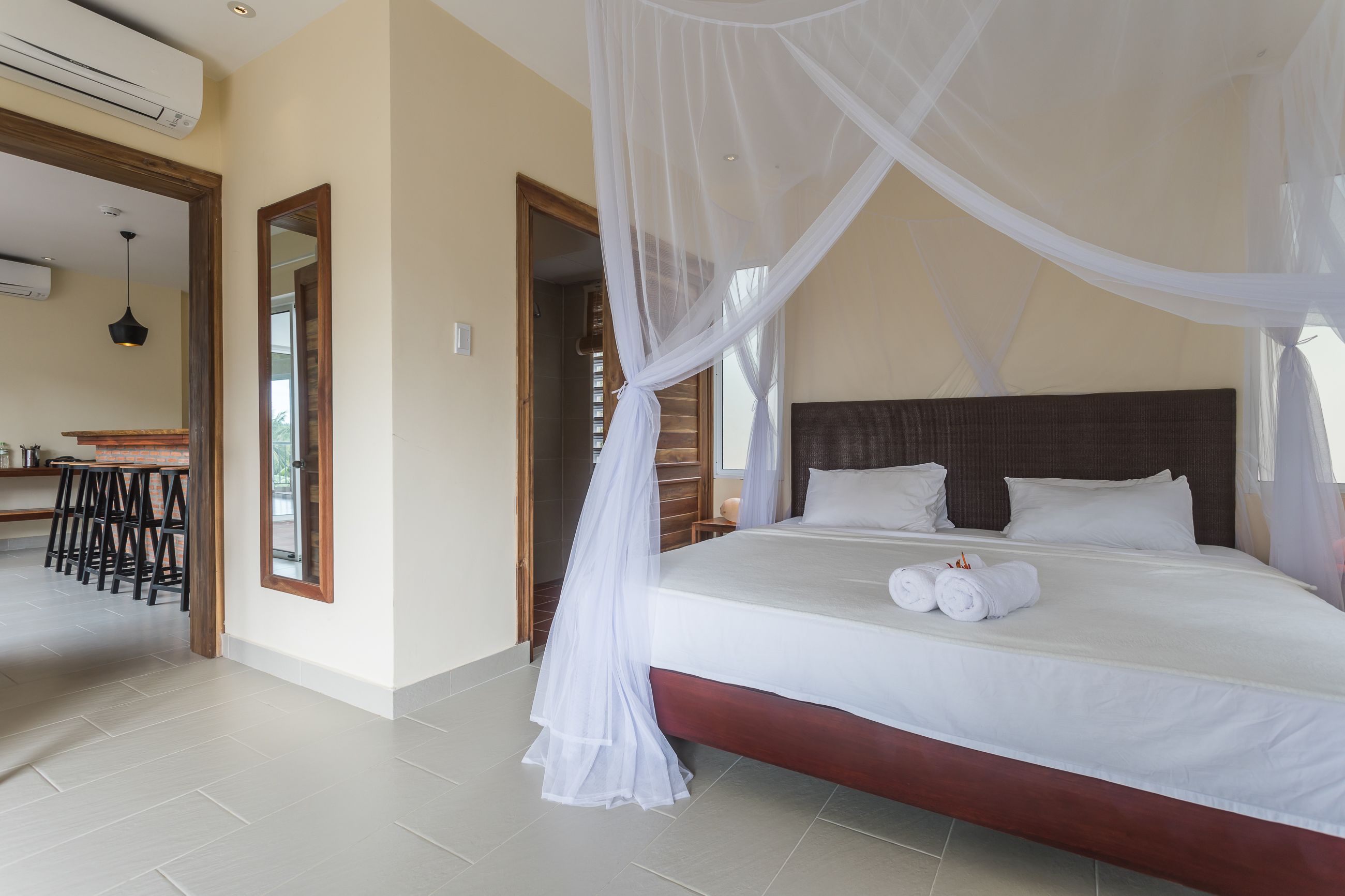 Quarto com cama, cortinas brancas e ventilador de teto.