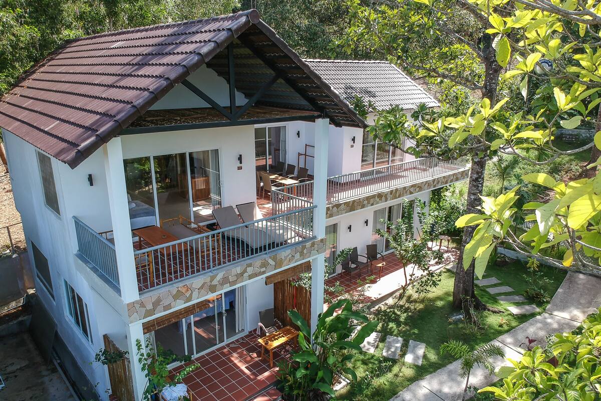 A two-story house with a balcony, a patio, and a garden.