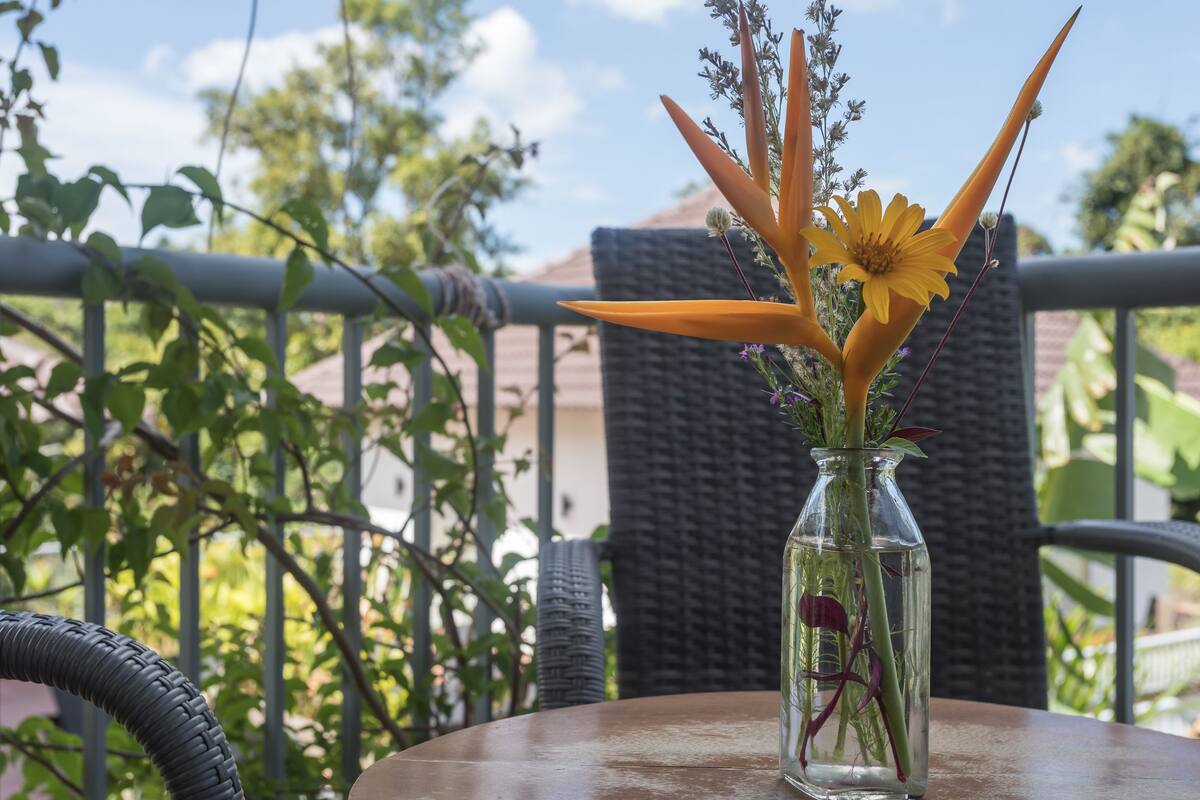 A clear glass vase with flowers on a round table outdoors.