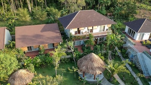 A resort with multiple buildings, a central courtyard with a thatched-roof structure, and a staircase leading to a second level. - Le Forest Resort (Phu Quoc)