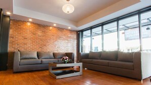A modern living room with two sofas, a coffee table, and a brick wall. - Coconut Budget and Boutique Huahin (Hua Hin)