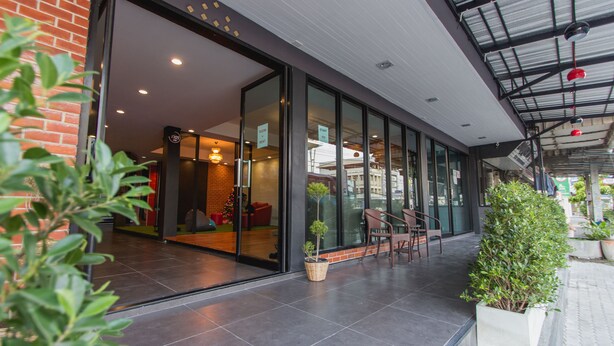 A modern building with large glass doors, a brick wall, and a tiled floor. - Coconut Budget and Boutique Huahin (Hua Hin)