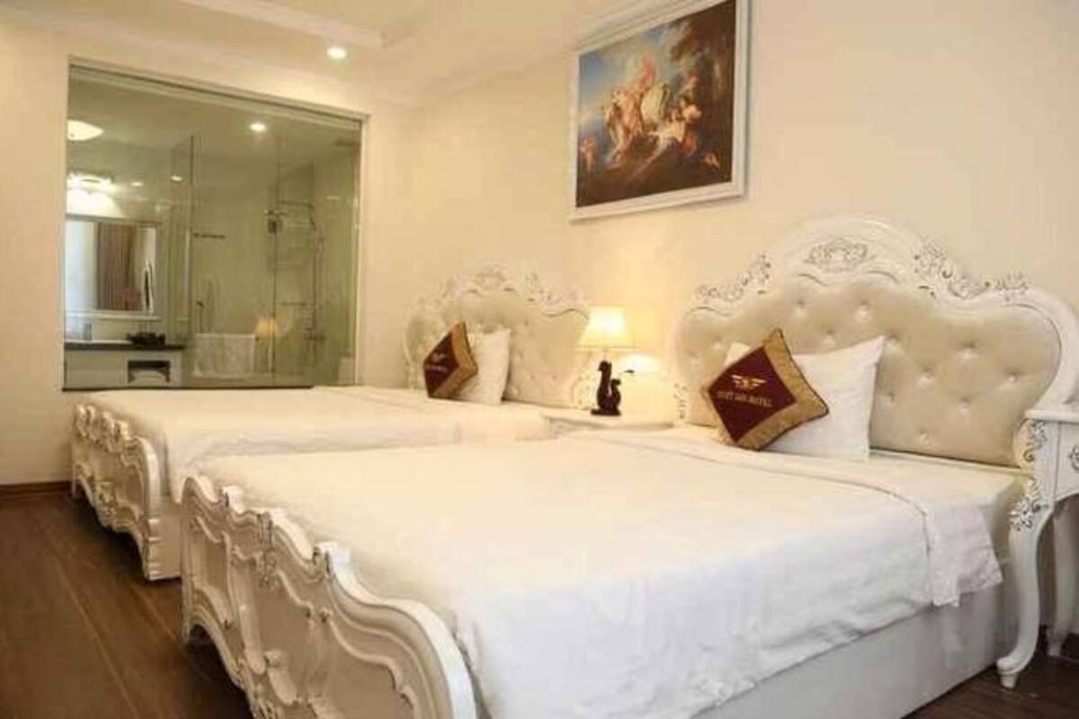 Quarto de hotel com duas camas elaboradas, um espelho grande e um quadro na parede.
