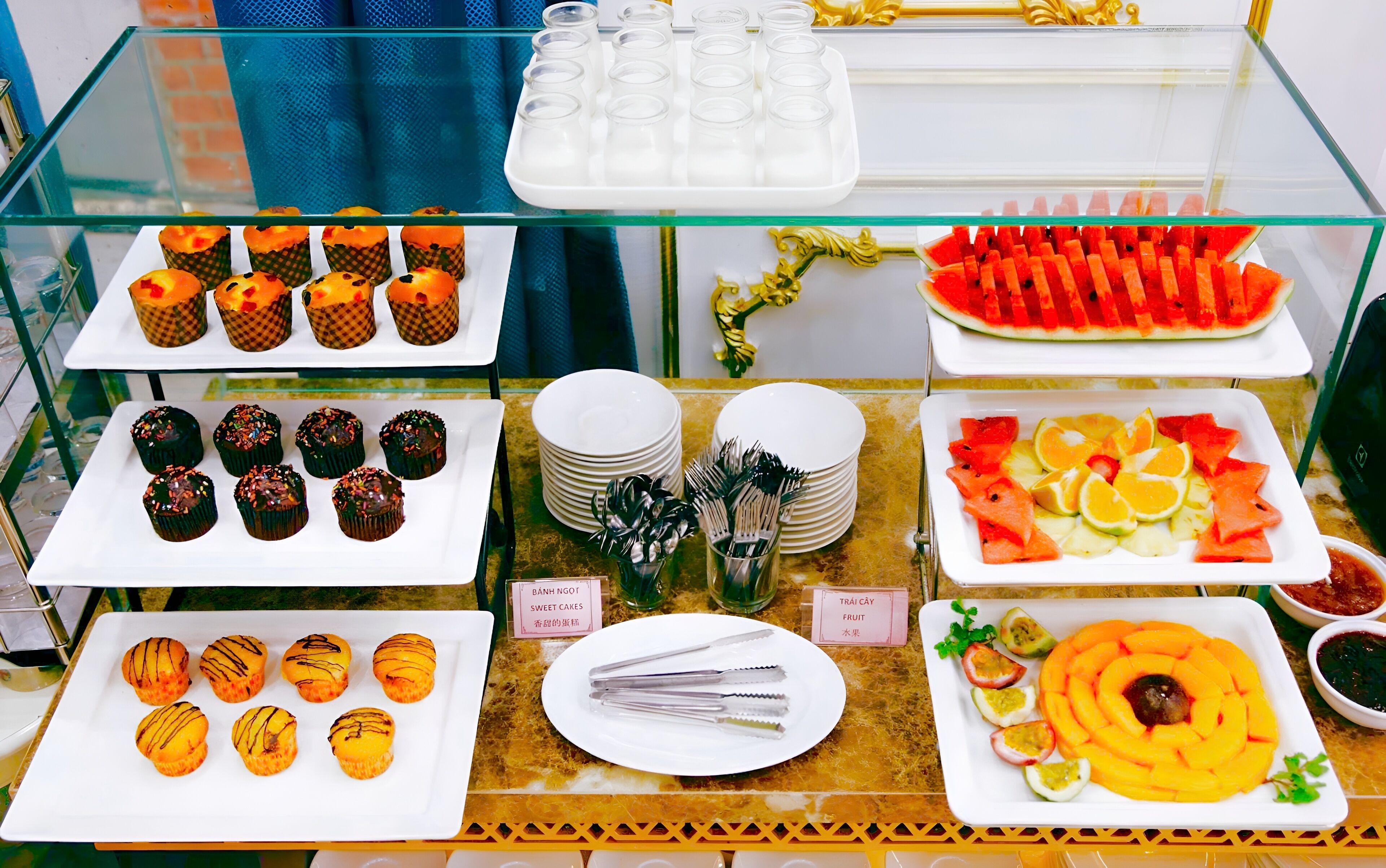 A buffet with various food items including cupcakes, fruit, and desserts.