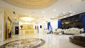 A luxurious hotel lobby with a grand reception desk, elegant sofas, and a large, ornate circular floor design. - Tuyet Son Hotel (Da Nang)