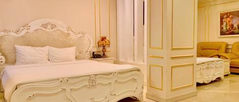 A luxurious bedroom with a large ornate bed, a matching nightstand, and a yellow armchair.