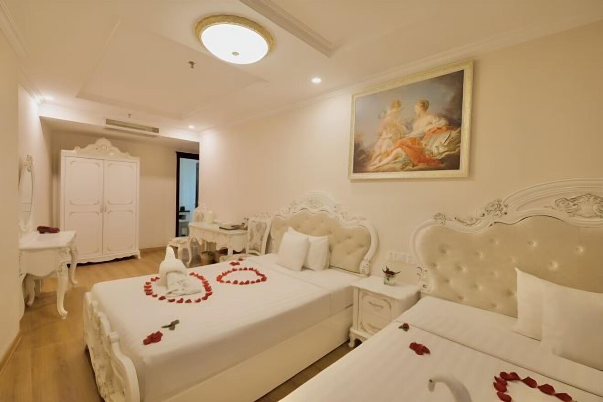 Una camera d'albergo con due letti, un armadio bianco, una scrivania e un quadro appeso al muro.