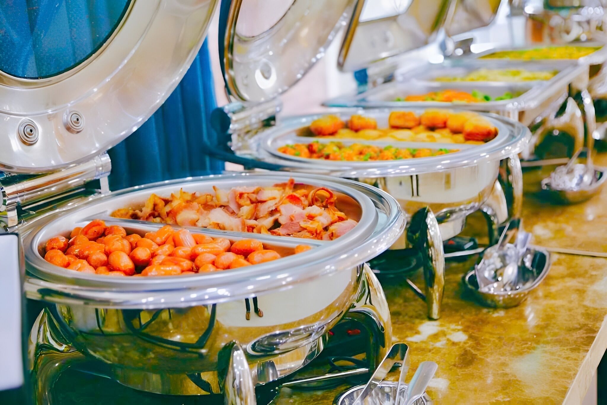 A buffet with various food items in metal serving dishes.