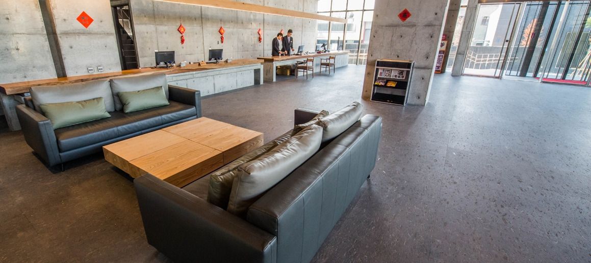 Un vestíbulo espacioso con sofás de cuero, una mesa de centro de madera y un mostrador de recepción.