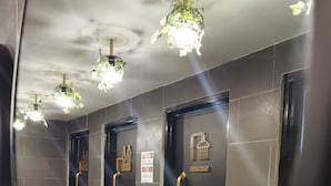A public restroom with multiple stalls, a sink, and decorative ceiling lights. - Aloha Capsule Hostel (Semporna)