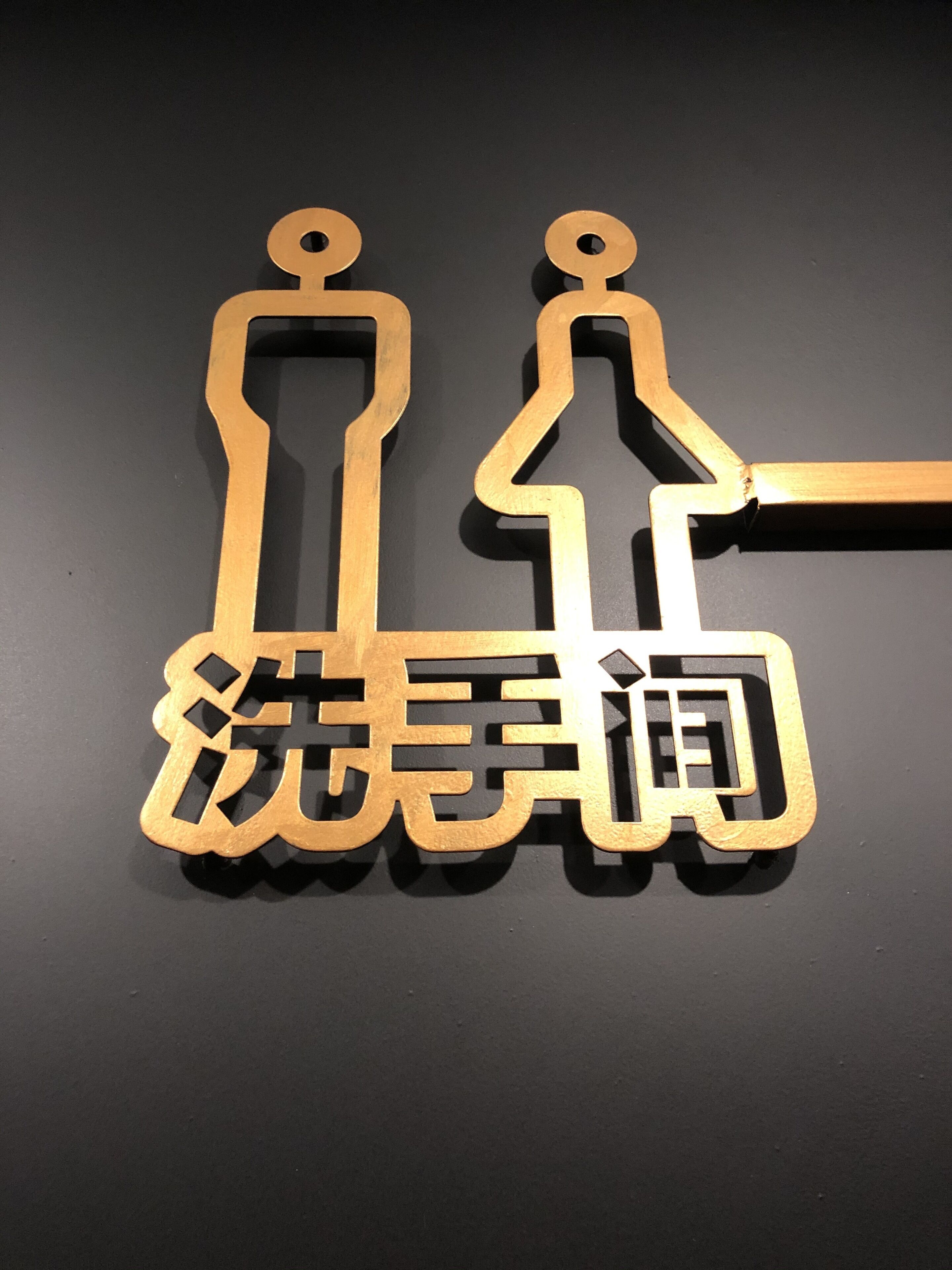 A wooden sign with Chinese characters and a silhouette of a building.