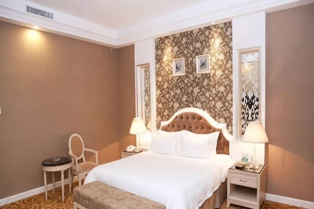 A hotel room with a large bed, two bedside tables with lamps, a chair, and a small round table.