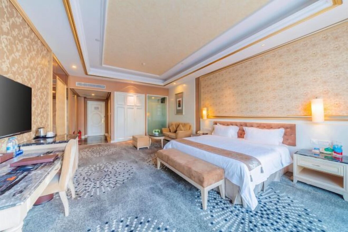 Ein Hotelzimmer mit einem großen Bett, einem Schreibtisch, einem Fernseher und einer Sitzecke.