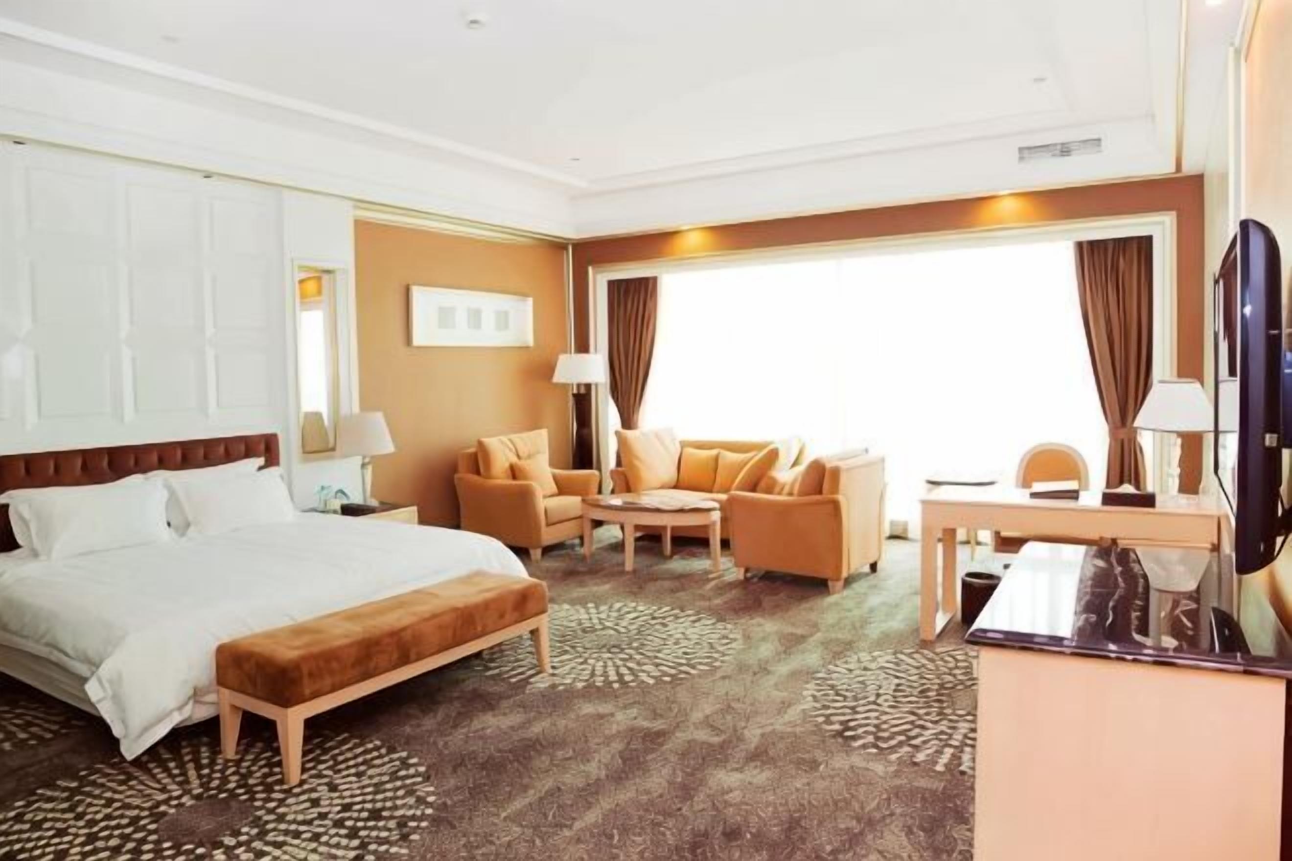 Una habitación de hotel con cama, sofá, escritorio y televisión.