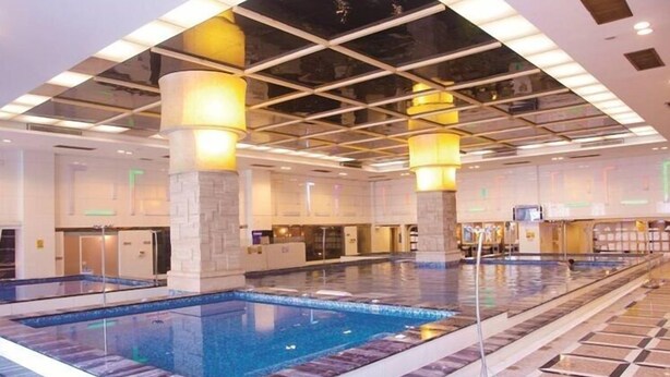 A large indoor swimming pool with clear water, surrounded by a tiled floor and walls, and illuminated by overhead lighting. - Dongguan Silver Holiday Hotel (Dongguan)