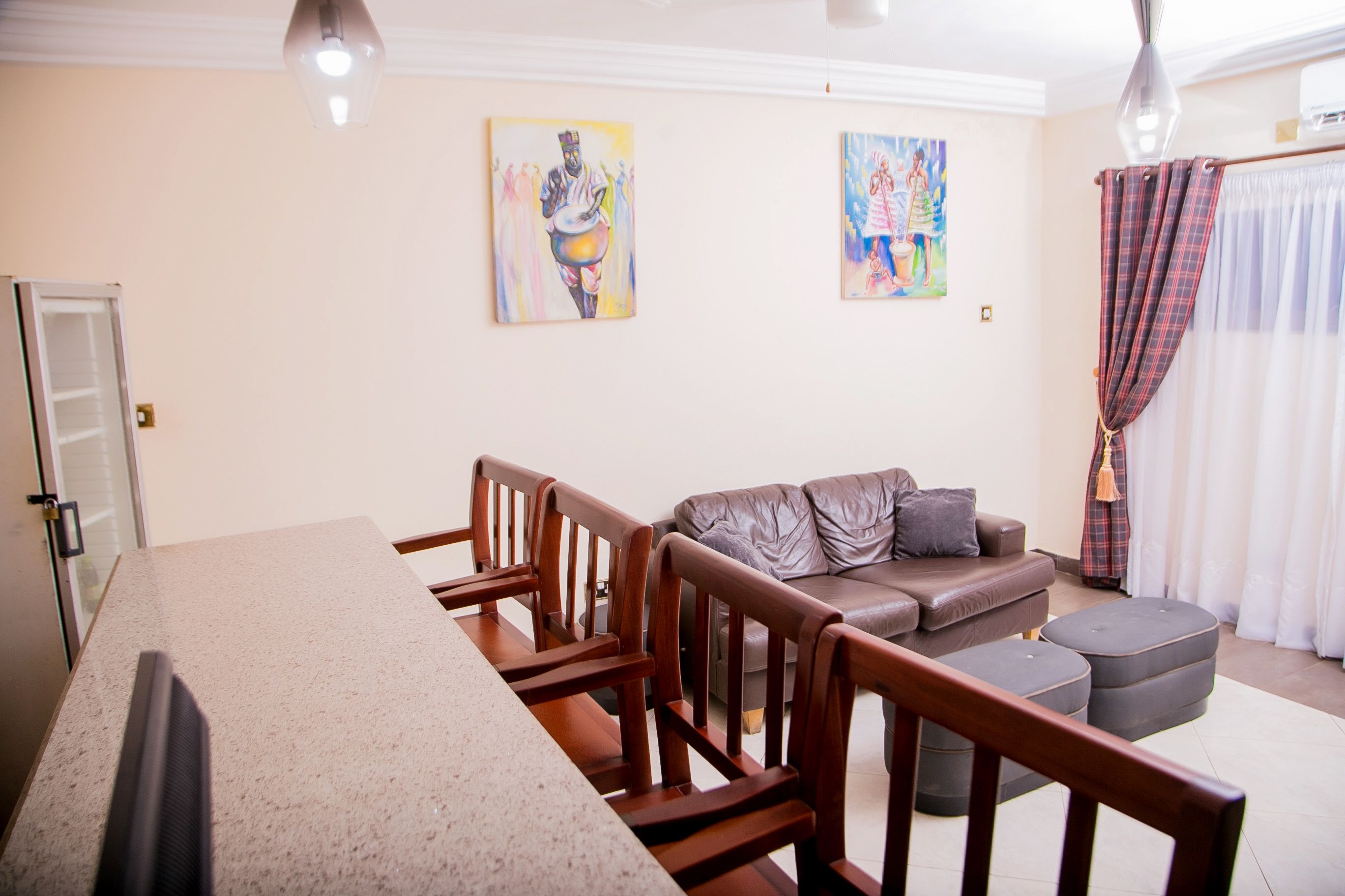 A modern living room with a dining area, featuring a sofa, chairs, a coffee table, and artwork on the walls.
