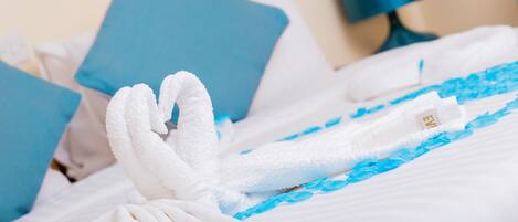 Un letto rifatto con cura, lenzuola blu e bianche, un asciugamano bianco e un cuscino blu.