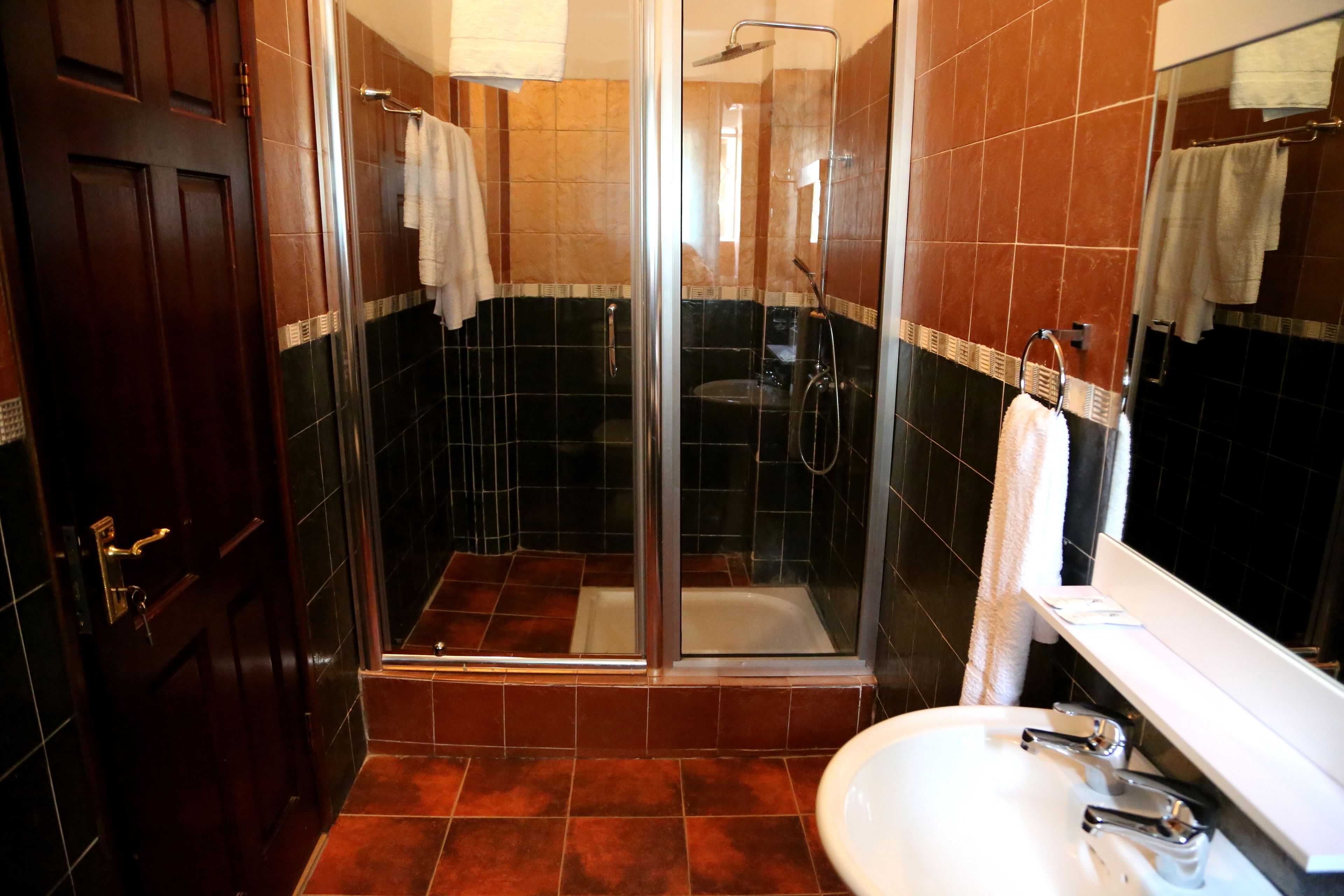 A bathroom with a glass-enclosed shower, a white sink, and a mirror.