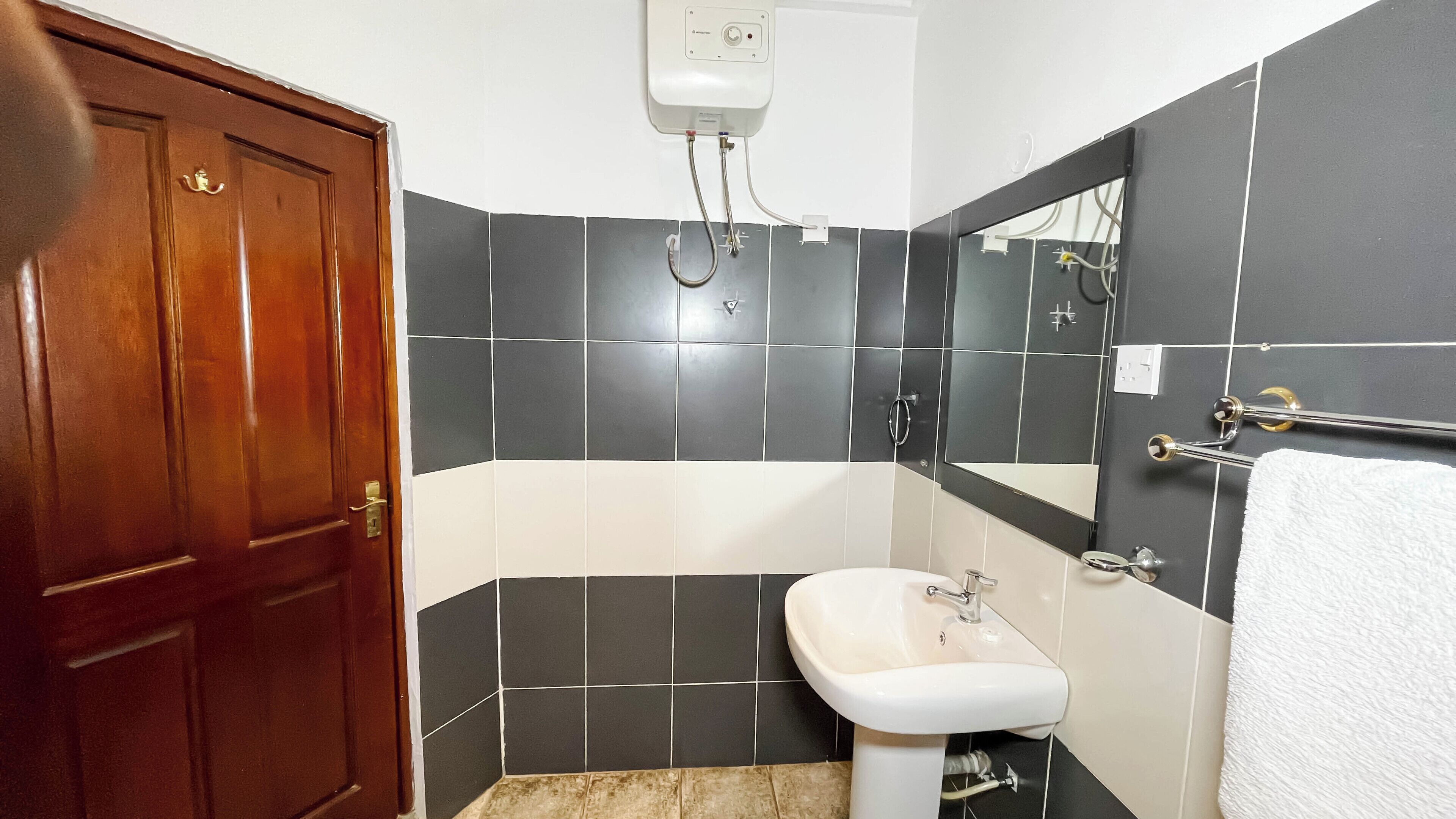 Un baño con puerta de madera, un lavamanos blanco, una bañera y un espejo.