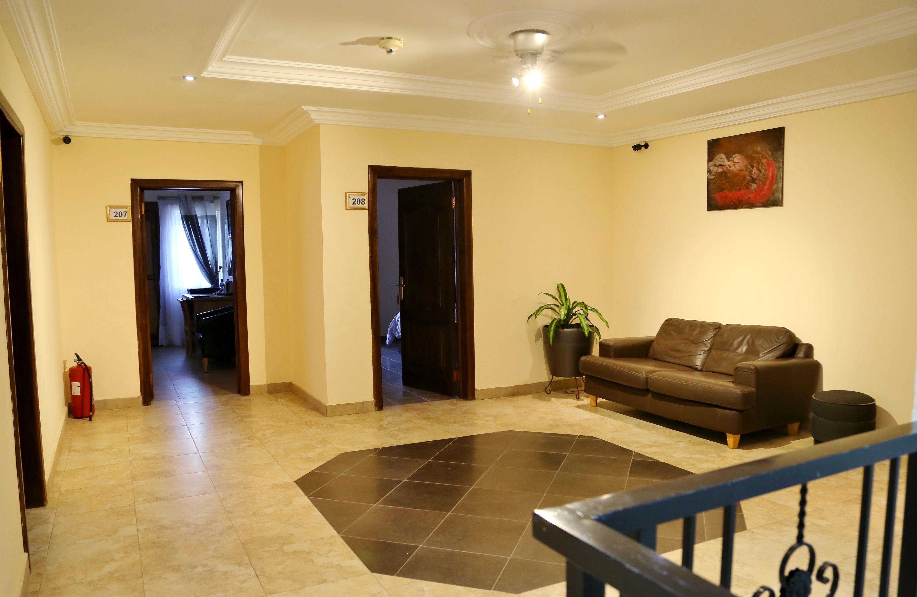 A hotel lobby with a brown leather sofa, a potted plant, and a fire extinguisher.