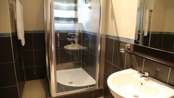 A bathroom with a glass-enclosed shower, a sink, and a mirror.
