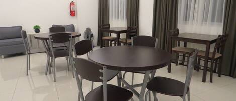 Un comedor moderno con una mesa redonda y sillas, un sofá y un extintor en la pared.