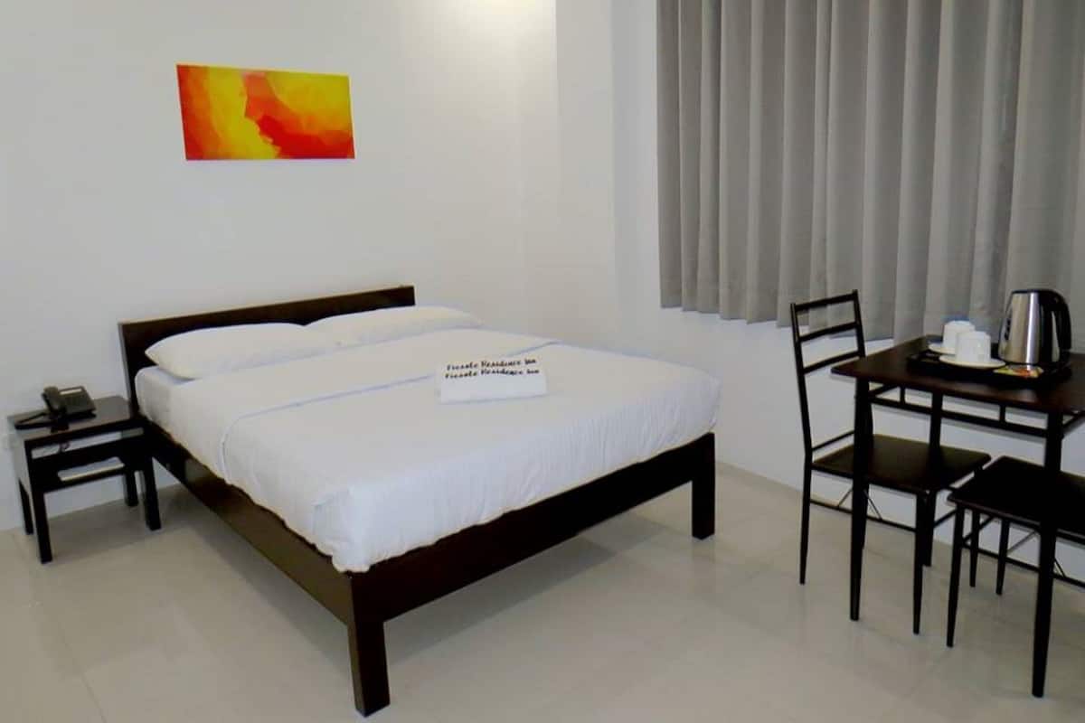 Una habitación de hotel con una cama, un escritorio con una silla, un teléfono y un cuadro en la pared.