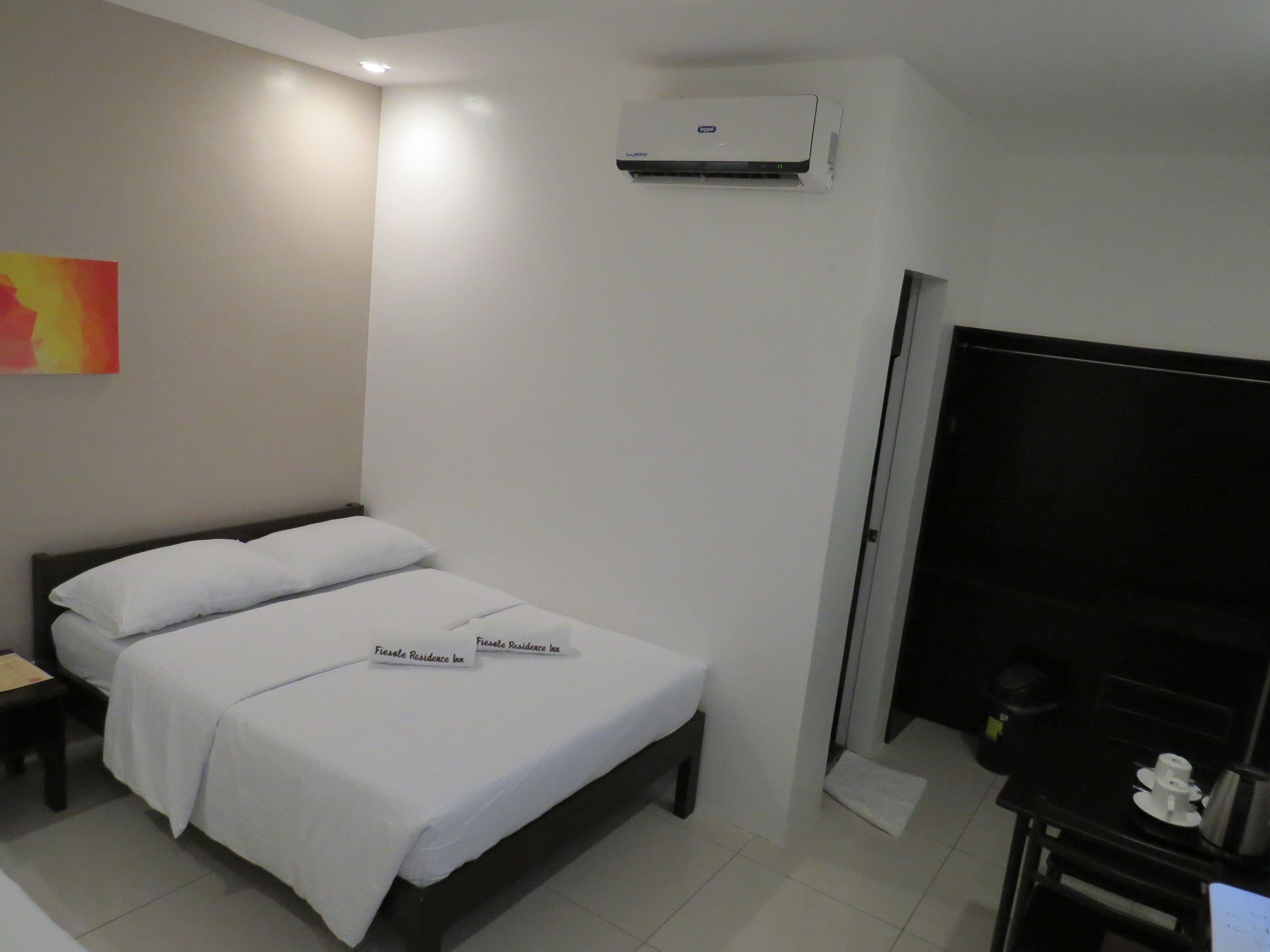 Ein Hotelzimmer mit Bett, Nachttisch, Klimaanlage und Fernseher.
