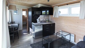 Eine kompakte Küche mit modernen Geräten, ein Essbereich mit Tisch und Stühlen sowie eine gemütliche Sitzecke mit einer Couch.