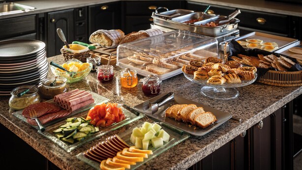 Ein Buffet mit verschiedenen Speisen, darunter Fleisch, Käse, Obst und Backwaren.