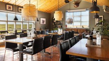 A spacious dining area with high ceilings, large windows, and a view of the outdoors.