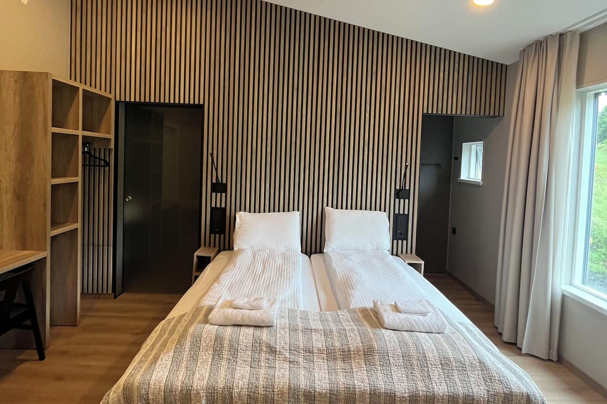 Quarto de hotel moderno com uma cama grande, armário embutido e vista para o exterior.